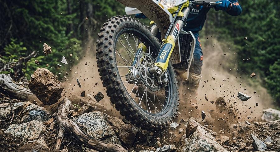 An enduro bike's front wheel driving through loose rock